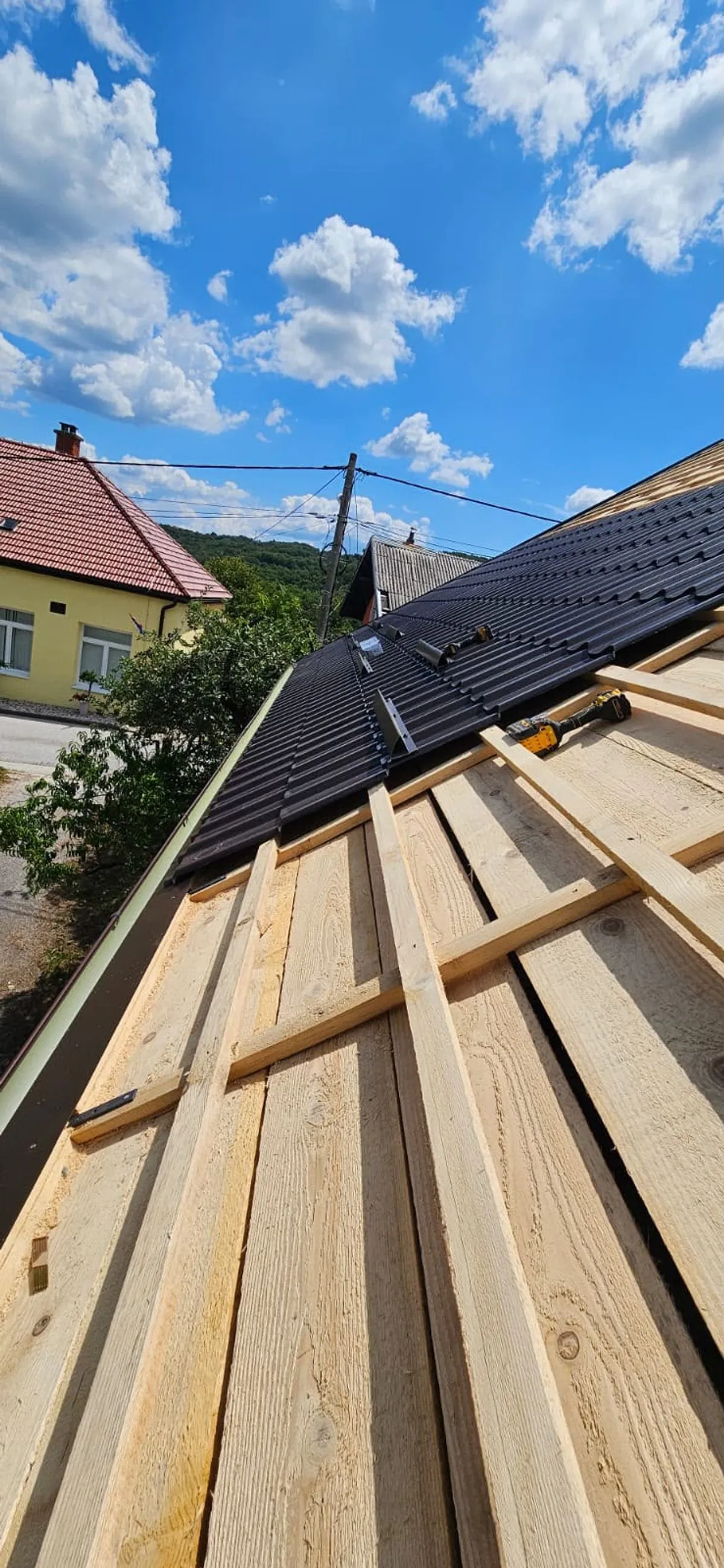 Țiglă metalică antracit în curs de montaj peste șipcile noi de lemn