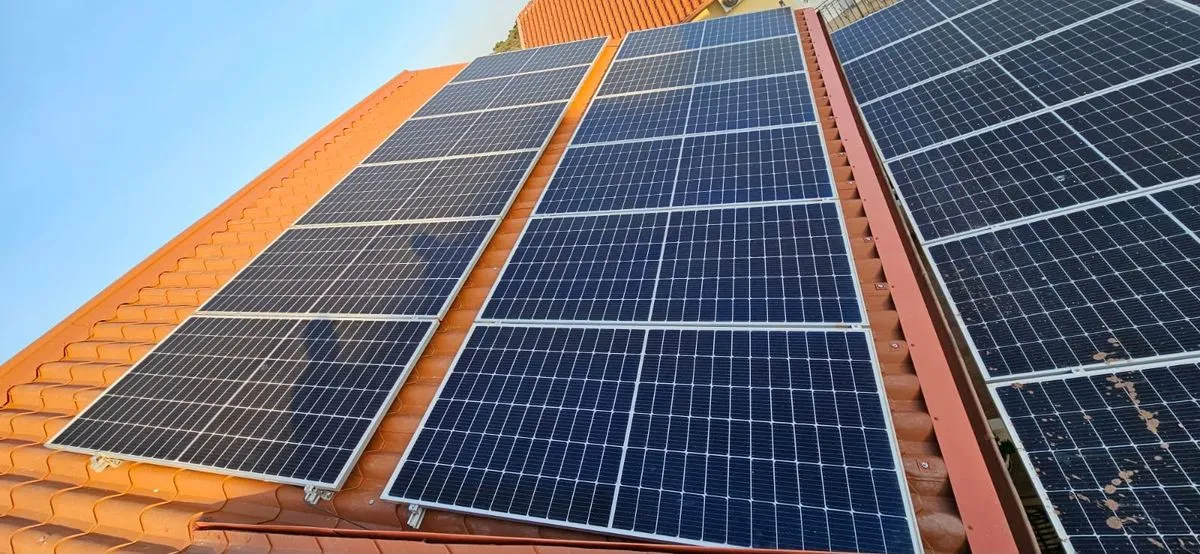 Panouri fotovoltaice montate pe un acoperiș cu învelitoare metalică portocalie