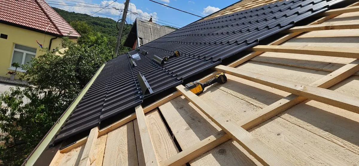 Montaj de țiglă metalică antracit, cu uneltele echipei pe acoperiș