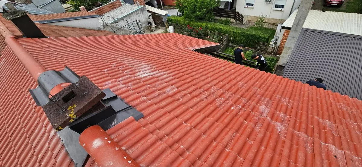 Acoperiș de țiglă roșie văzut de sus, cu echipa la lucru pe margine
