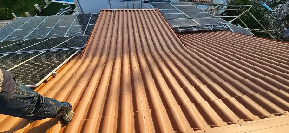 Țiglă ceramică portocalie, cu panouri fotovoltaice montate alături